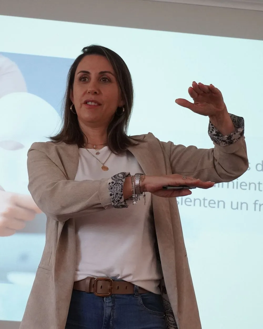 Carolina Vega explicando con las manos durante un taller, frente a una presentación.